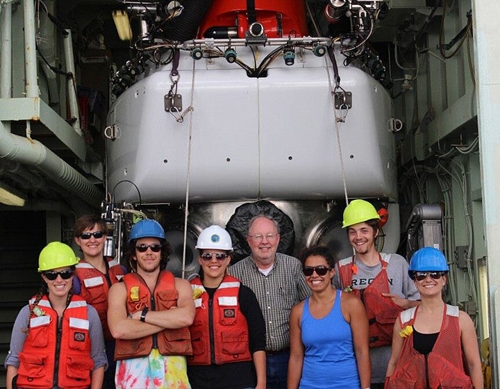 Group of researchers standing together in front of a research vessel