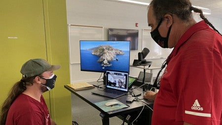 Two men look at a computer screen