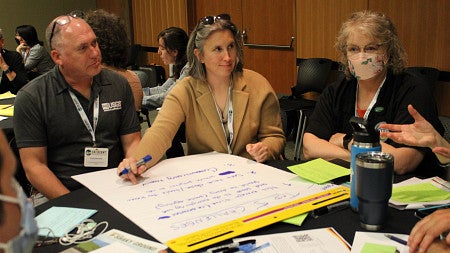 people sitting at a table, talking with a large notepad on the table