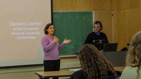 A teacher lecturing a class while another stands in the background