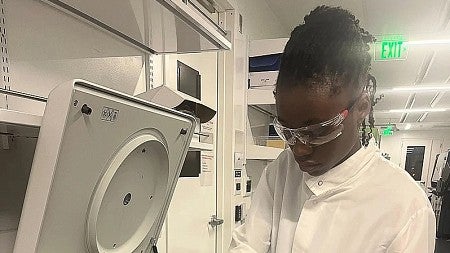 a person working in a lab wearing a white lab coat and safety glasses