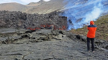 a man stands next to a lava flow