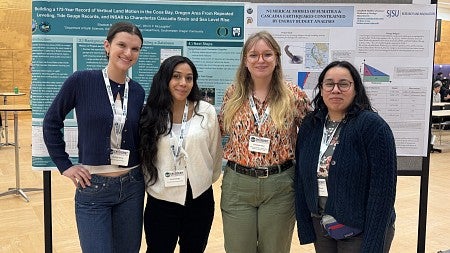 four students standing in front of a poster