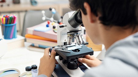 back of student head looking into a microscope