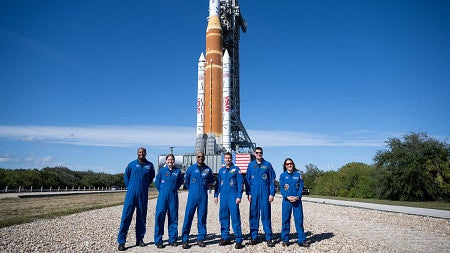 a group of people stand in front of a rocket