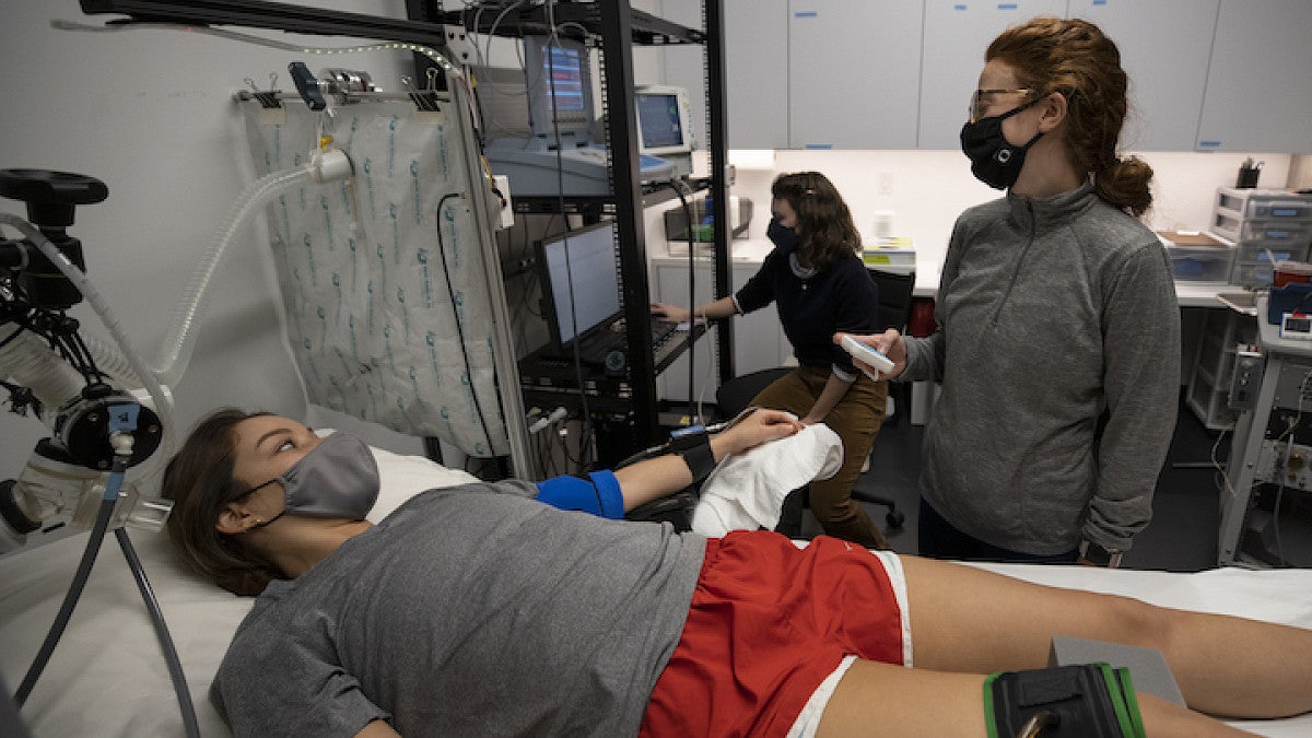 person lying on exam table with equipment on knee, with other people monitoring