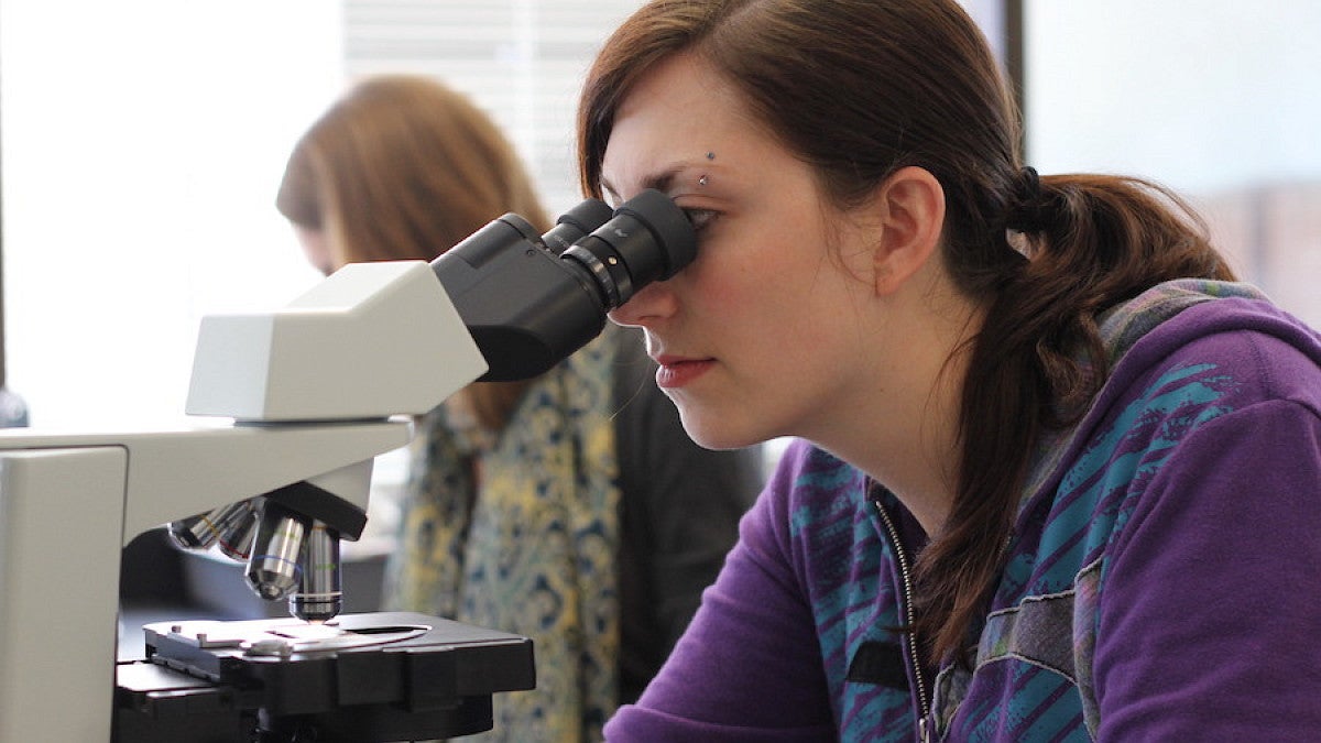 student looking into microscope