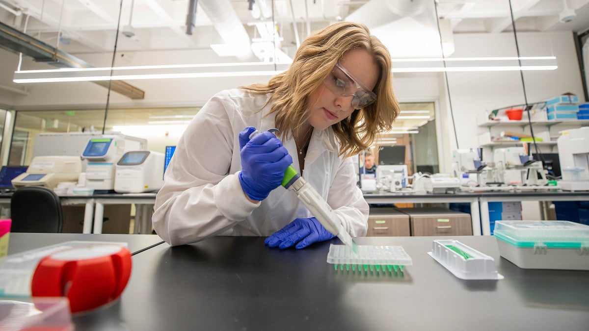student in lab using pipette