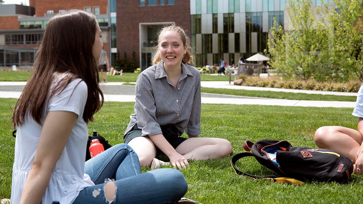 students sitting on campus lawn