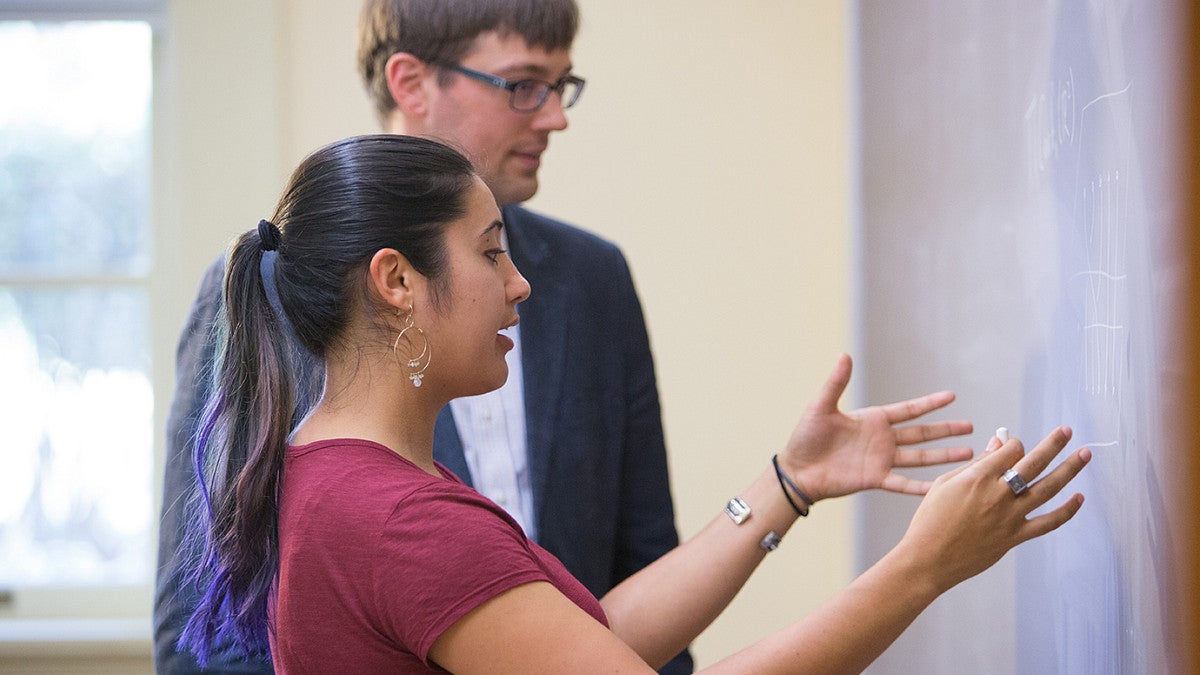 student and professor talking near chalkboard