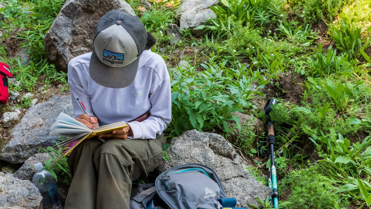Student sitting on a rock writing
