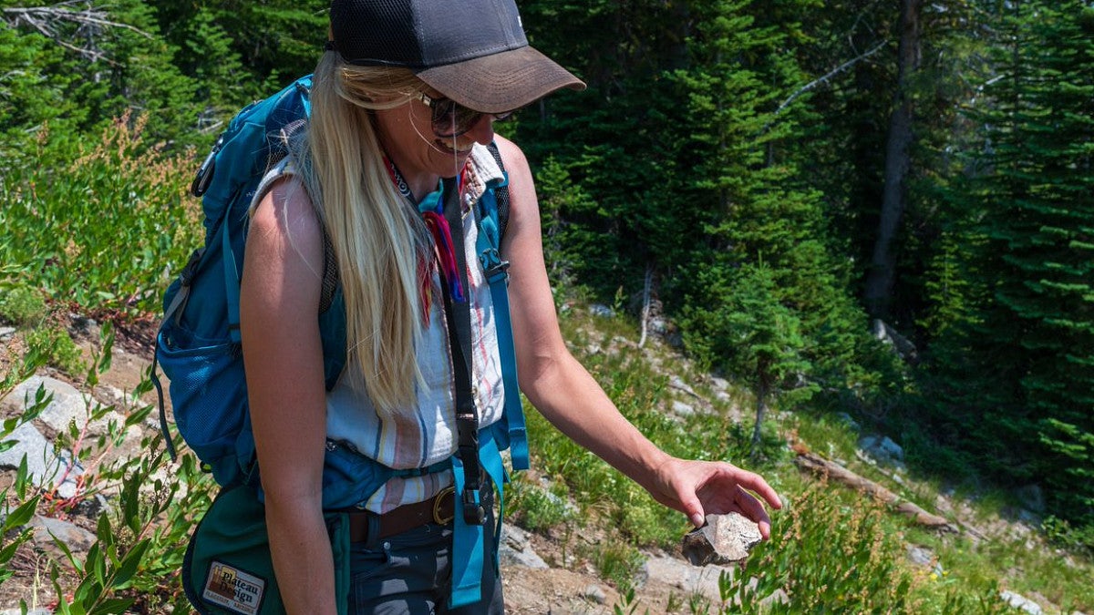 Student on a trail holding a rock