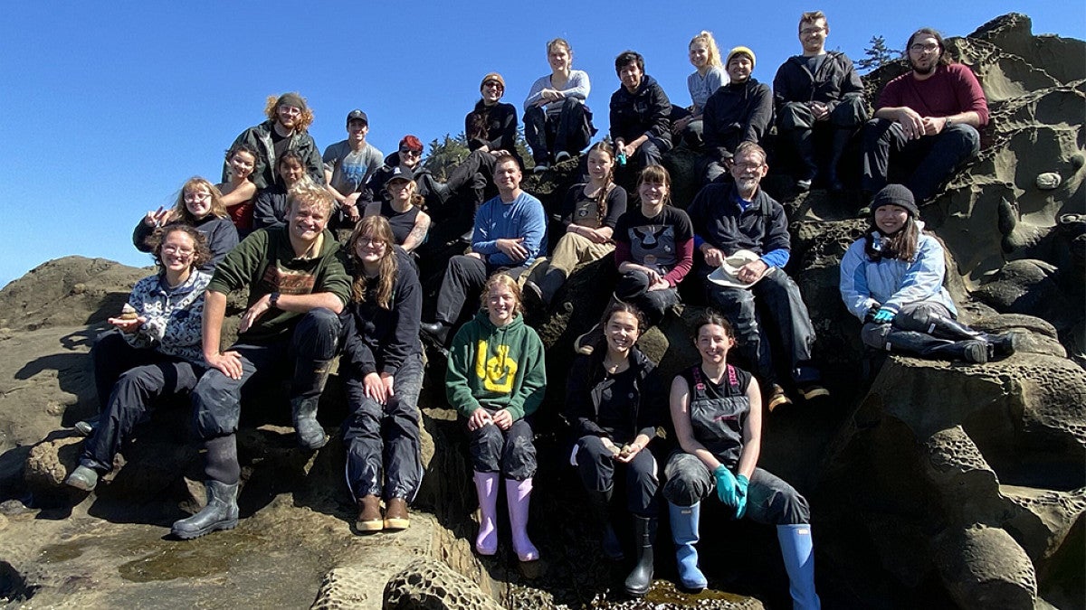 Group of researchers and students sitting on rocks for a group photo