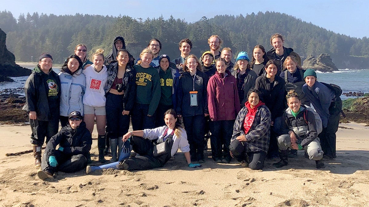 Group of marine biology students posing for  group photo on a beach