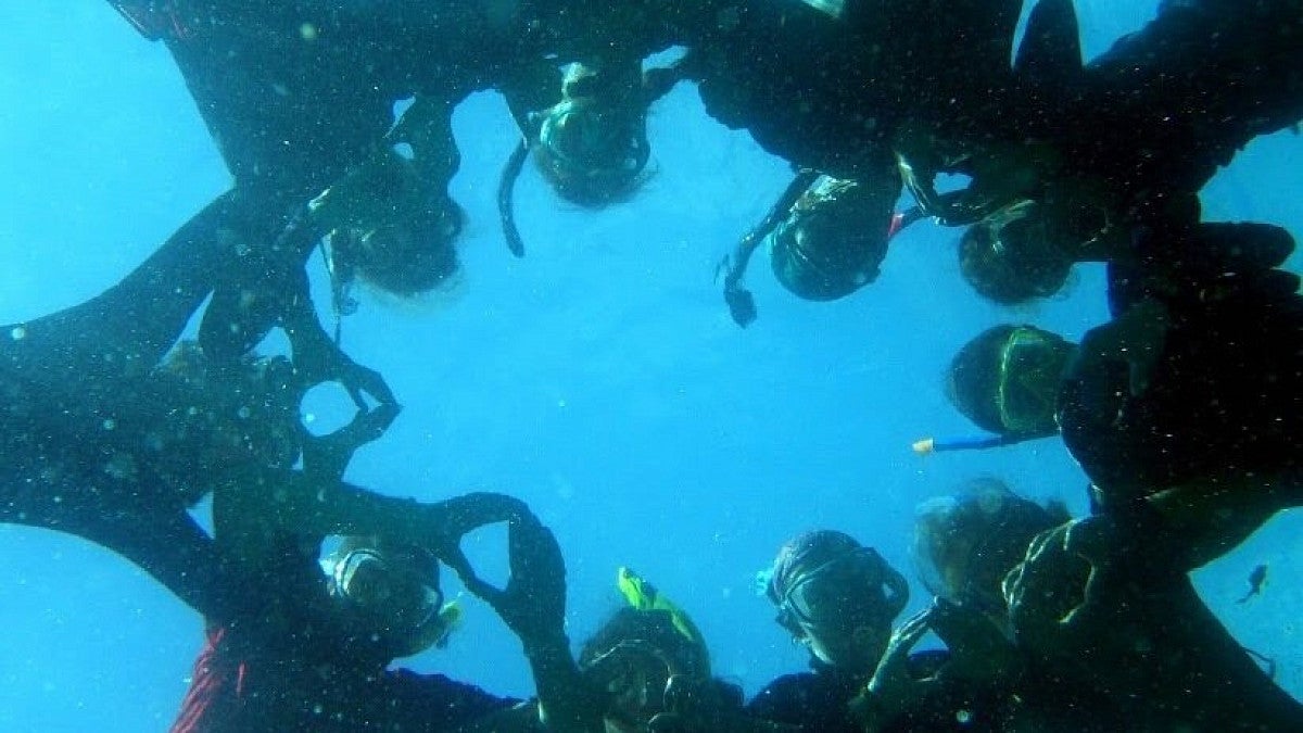 Group of students snorkeling forming an "o" in the ocean