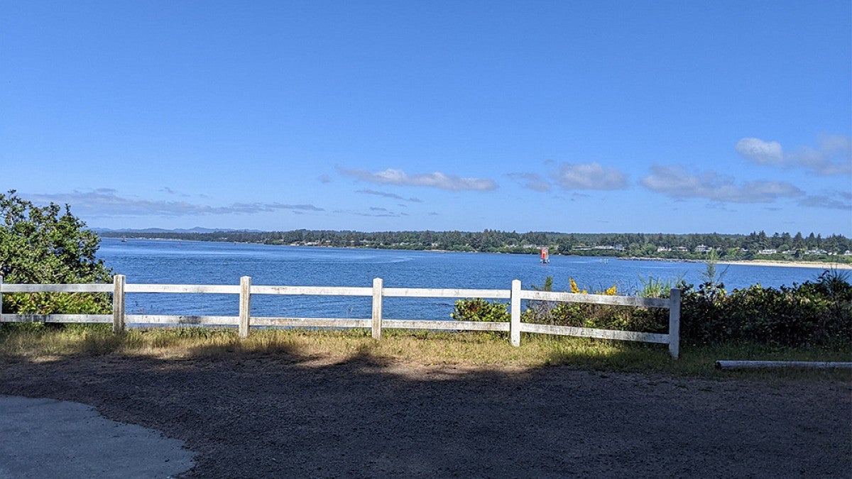 Cliffside with white fence overlooking the ocean with coastline in the distance