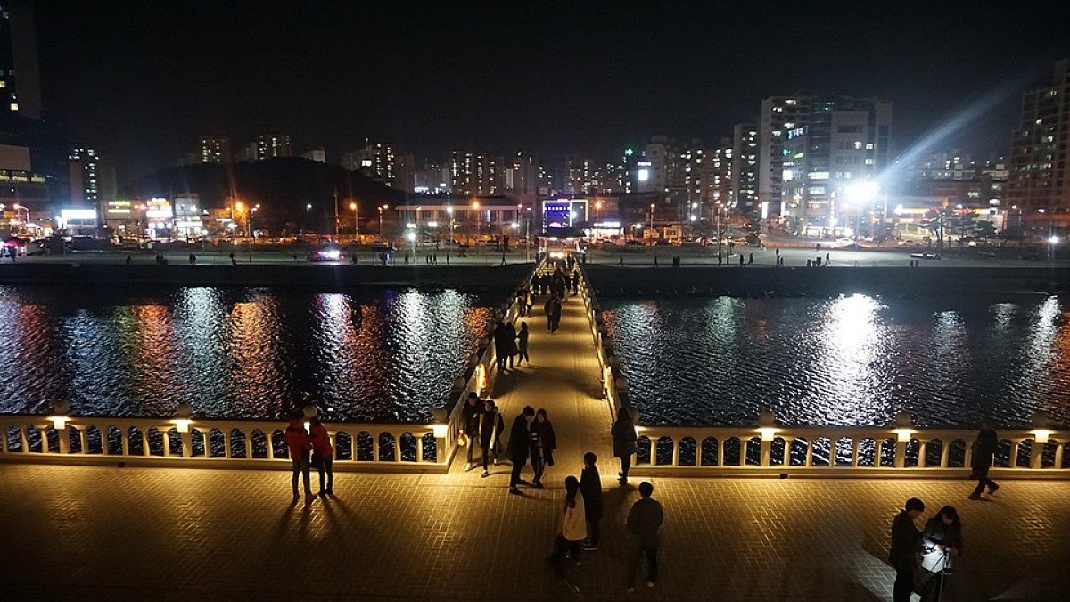 A cityscape at night with a river in the foreground