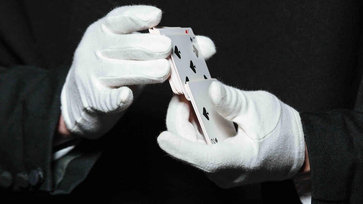 a person shuffles cards wearing white gloves