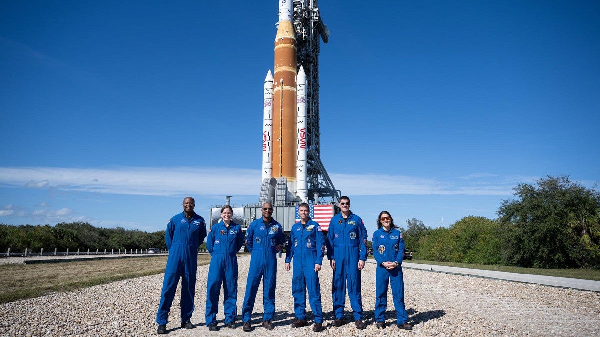 a group of people stand in front of a rocket
