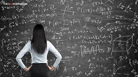 a woman looking at a chalkboard filled with math equations