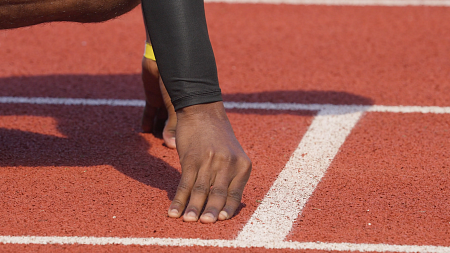 a person's hands on a track, ready to start running