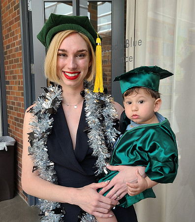 Psychology alum Kelly Robles holding a baby at graduation