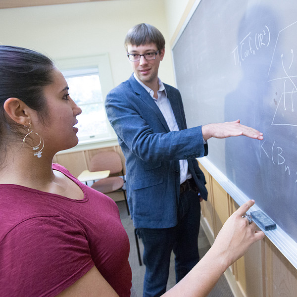 student and professor talking near chalkboard